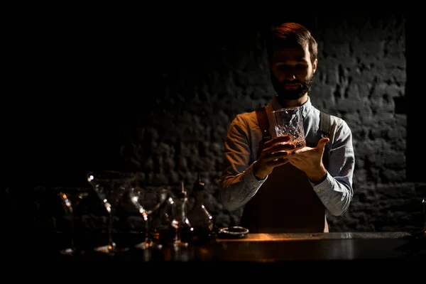 Martini bardaklarının önünde barmen ve tezgahın üzerinde acı dolu şişeler. — Stok fotoğraf