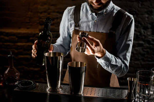 Cantinero macho sirviendo una bebida alcohólica del jigger de acero a una coctelera —  Fotos de Stock