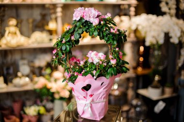 Pembe renkli güllerle kaplı yeşil bir sepet.