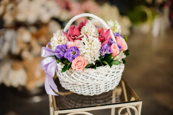 Cesta branca com rosas roxas, jacinto branco e orquídeas rosa suculentas na mesa — Fotografia de Stock