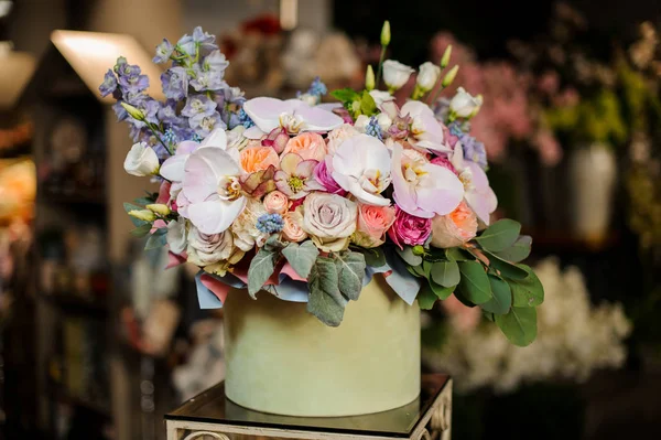 Boîte ronde verte pleine de différentes roses de couleur tendre, orchidées et clochettes décorées de feuilles vertes — Photo