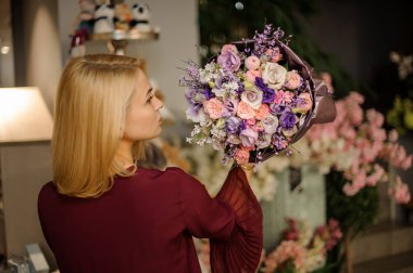 Sarışın, kısa saçlı buketli poz veren.