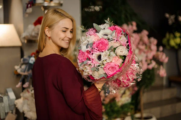 Chica rubia sonriente disfrutando de su ramo de flores — Foto de Stock