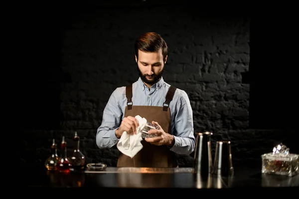 Professionell bartender står på bardisken gnuggar glaskoppen med en trasa — Stockfoto