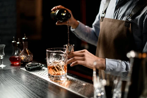 Barman nalewa napój alkoholowy z butelki do stalowego jiggera — Zdjęcie stockowe