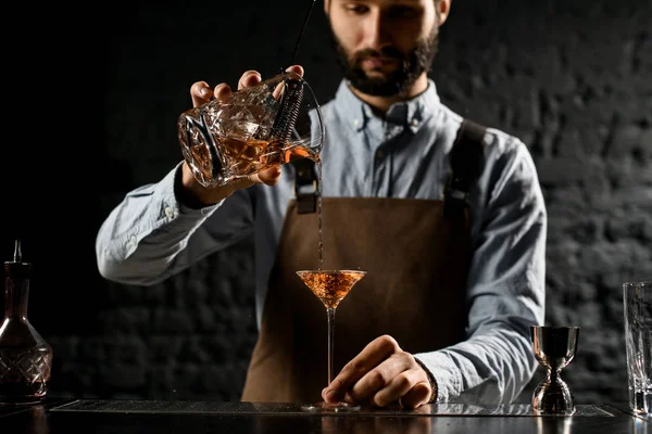 Бармен наливает алкогольный напиток в бокал мартини, наполненный льдом — стоковое фото