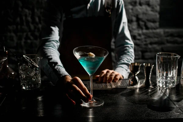 Barman serwujący niebieski koktajl alkoholowy w kieliszku martini ozdobionym suchym kolcem — Zdjęcie stockowe