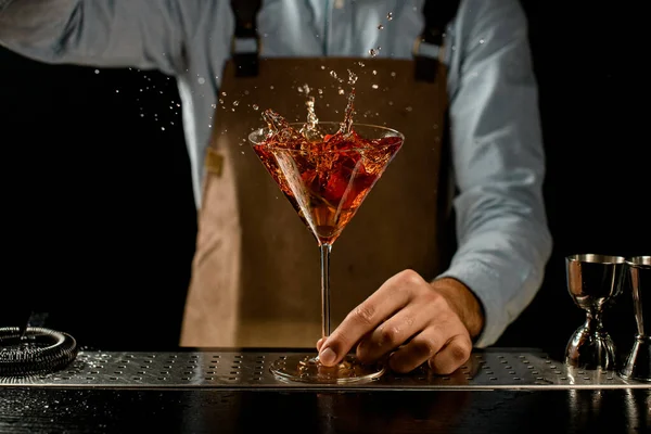 Profissional barman masculino jogando um botão de rosa vermelha para um copo de martini com um coquetel de ouro — Fotografia de Stock