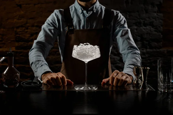 Бармен стоит на барной стойке с большим стаканом со льдом — стоковое фото