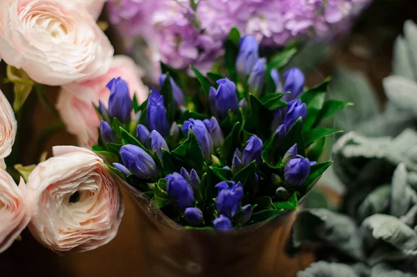 Kytice z modrých tulipánů se zelenými listy v průhledném balicím papíru — Stock fotografie