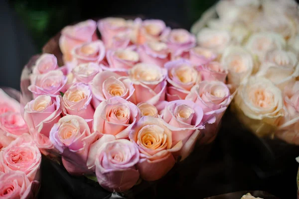 Прекрасный букет розовых персиковых роз в прозрачной оберточной бумаге — стоковое фото