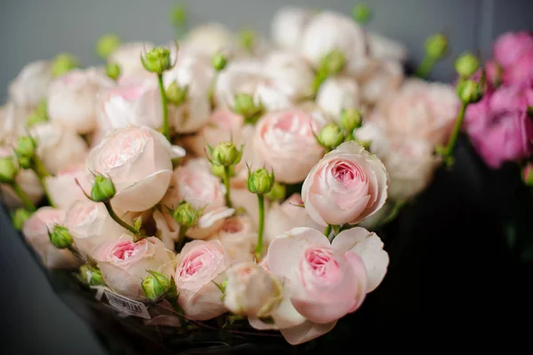 Красивый букет нежных розовых роз с закрытыми зелеными бутонами в прозрачной оберточной бумаге — стоковое фото