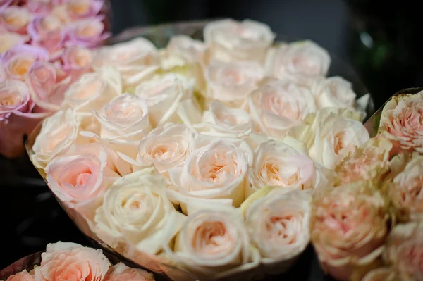 Прекрасный букет нежных сливочных цветных роз в прозрачной оберточной бумаге — стоковое фото