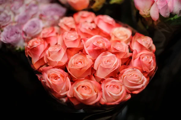 Прекрасный букет ярких персиковых роз в прозрачной оберточной бумаге — стоковое фото