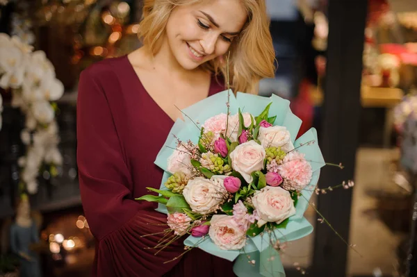 Chica sonriente sosteniendo un ramo de primavera de rosas rosadas tiernas, tulipanes y claveles decorados con hojas verdes — Foto de Stock
