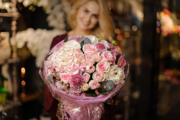 Mujer sosteniendo un ramo de primavera de rosas de color rosado tierno en el papel de embalaje —  Fotos de Stock