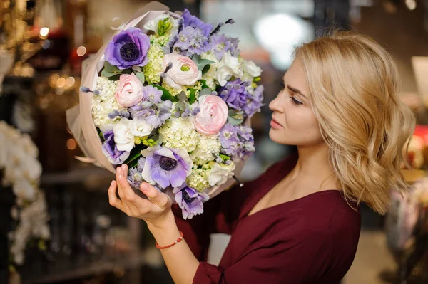 Mulher segurando um buquê de flores roxas, verdes e rosadas no papel de embrulho — Fotografia de Stock