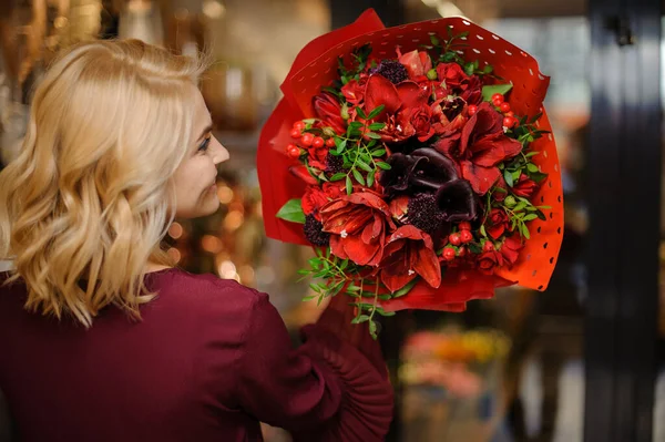 Woman holding a spring bouquet of bright red amaryllis with leaves and berries in the wrapping paper — 스톡 사진