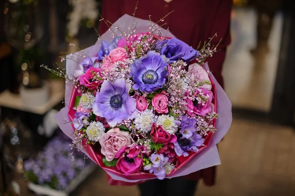 Mujer sosteniendo un ramo de primavera de tiernas flores de color púrpura, rosa y rosado en el papel de regalo —  Fotos de Stock