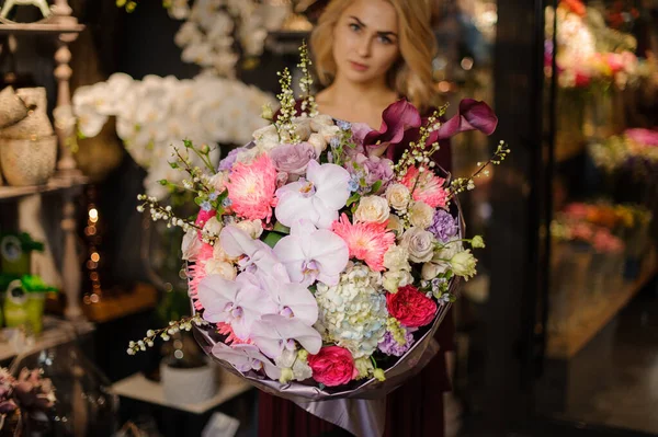 Mulher segurando um buquê de primavera de orachids rosa, hortênsias e rosas decoradas com ramos — Fotografia de Stock