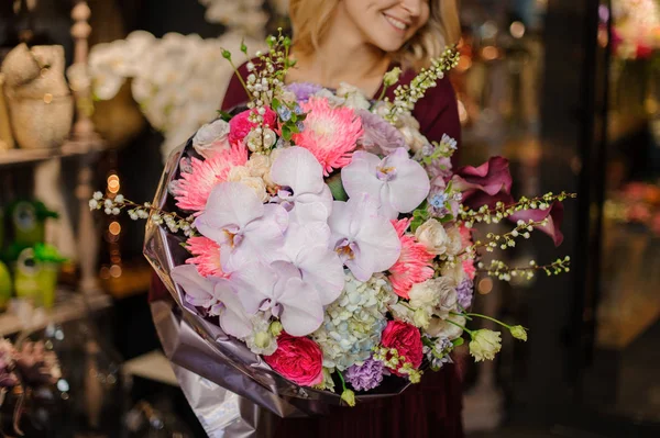 Menina sorridente segurando um buquê de primavera de orachids rosa, hortênsias e rosas decoradas com ramos — Fotografia de Stock