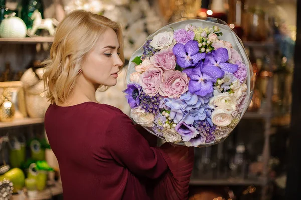 Muchacha trasera sosteniendo un ramo de primavera de orachids púrpura, hortensias y rosas cremosas envolver en papel — Foto de Stock