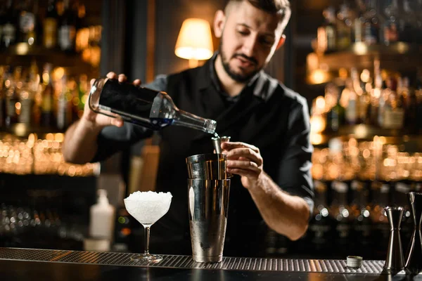 Mężczyzna barman nalewanie a alkohol napój z w butelka do a stalowy jigger — Zdjęcie stockowe