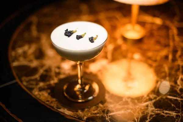 Смачний вершково-білий алкогольний напій у склянці коктейлю, прикрашений сухою квіткою — стокове фото