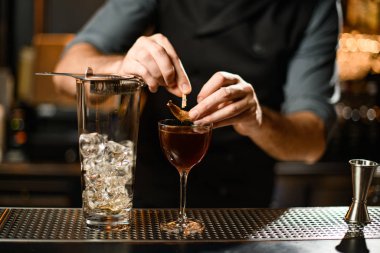 Profesyonel barmen, bardakta kurumuş bir yaprak ile kahverengi bir kokteyl süslemiş.