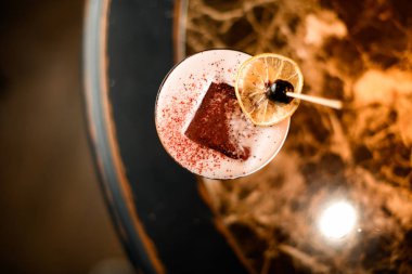 Bardakta pembe alkollü kokteyl, kurutulmuş portakal ve kürdanın üstünde böğürtlen.