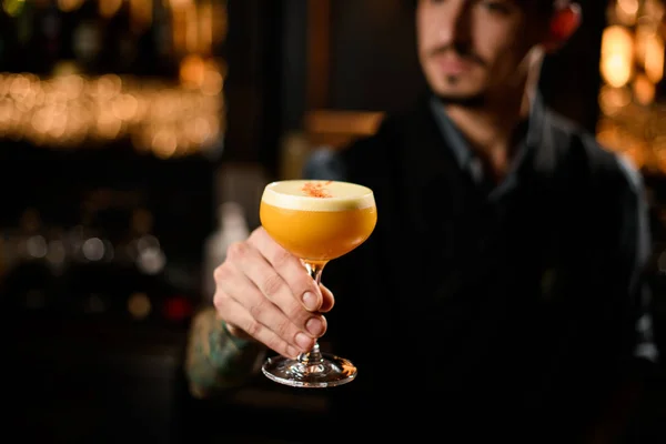 Bartender serving the orange alcoholic cocktail with a white scum decorated with zest — 스톡 사진