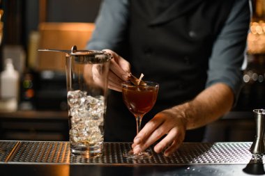 Kuru yaprakla alkol kokteyli hazırlayan barmenin yakın çekimi.