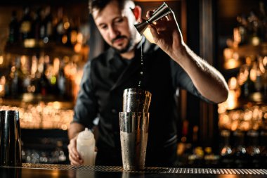 Erkek barmen alkolü jiggerdan karıştırıcıya düşürür.