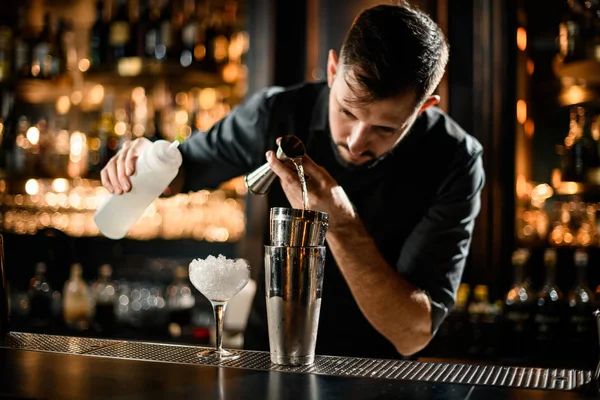 Male bartender precisely flows alcohol from jigger to glass — Stock Photo, Image