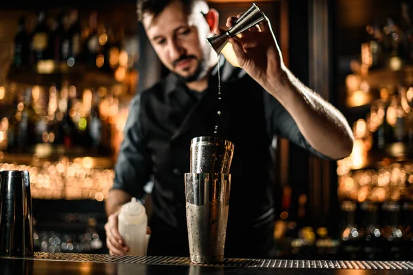 Man barman druppels alcohol van jigger naar cocktailshaker — Stockfoto