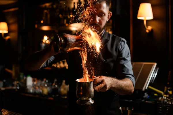 Cantinero macho vierte líquido ardiente de taza en taza — Foto de Stock