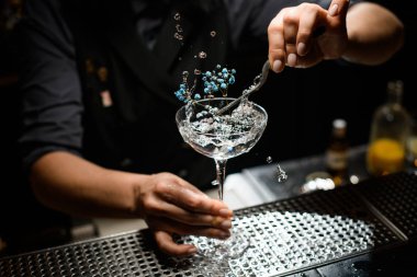 Kadın barmene yakın plan, alkol içeceğini küçük çiçeklerle süslüyor