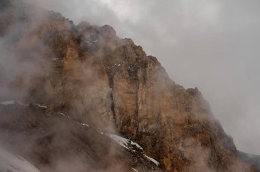 Beyaz sisin içinde, gökyüzünün altındaki kayalık tepe.