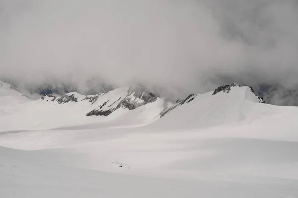 Paisagem da encosta montanhosa rochosa coberta de neve sob o céu — Fotografia de Stock