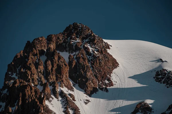 Brunt berg stenig med snö rester under den blå himlen — Stockfoto