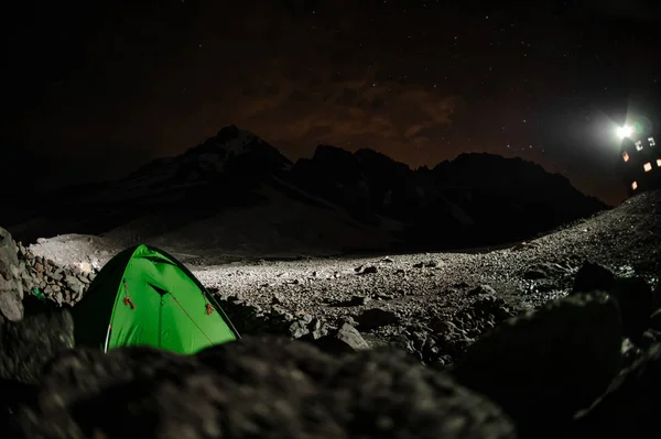 Landschaft des grünen Zeltes, das in der Nacht auf dem mit Felsen bedeckten Berg steht — Stockfoto