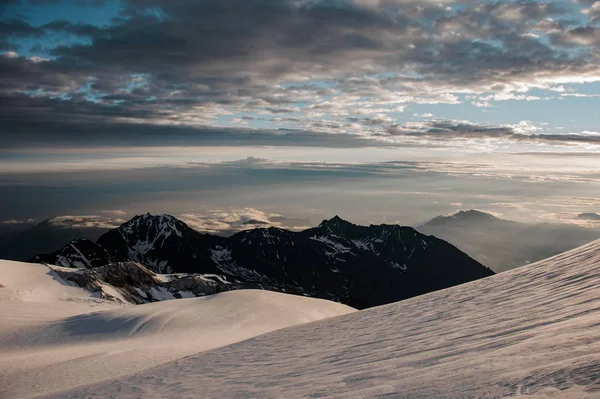 Вид на горы, покрытые снегом, под вечерним ясным небом с облаками — стоковое фото