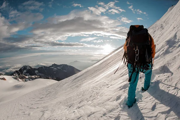 Dağın tepesindeki karlara tırmanan yürüyüş ekipmanlı adam. — Stok fotoğraf