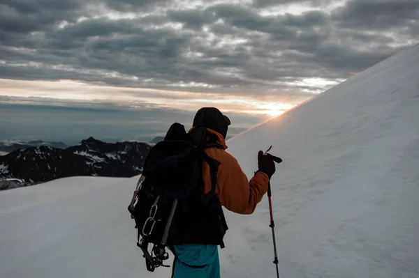 Zadní pohled muž s turistickým vybavením lezení na sněhu na horském kopci — Stock fotografie