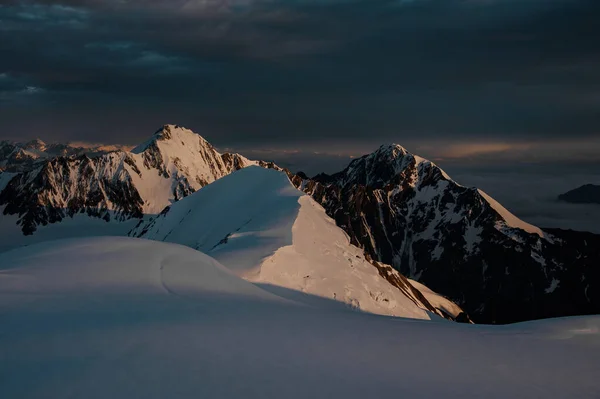Uitzicht op de bergen bedekt met sneeuw onder de avondhemel met donkere wolken — Stockfoto
