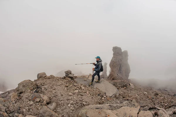 Man standing on the rocky mountain hill under the white fog — 图库照片