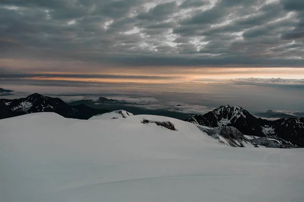 雲に覆われた夜空の下で雪に覆われた黒い山の景色 — ストック写真