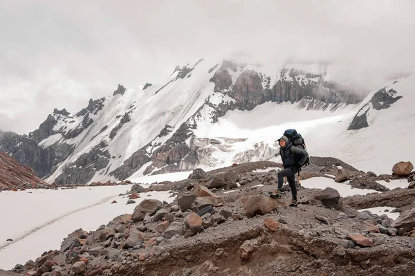 Человек, стоящий на скалах вокруг остатков снега в горах — стоковое фото