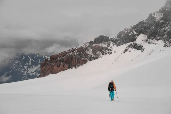 Человек с рюкзаком идет по склону горы — стоковое фото