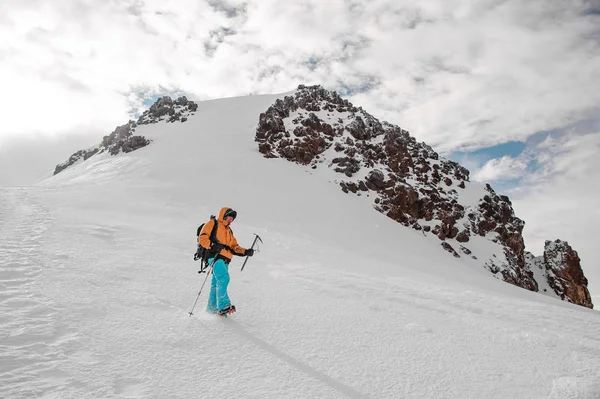Парень с туристическим снаряжением стоит на снегу на горном холме — стоковое фото